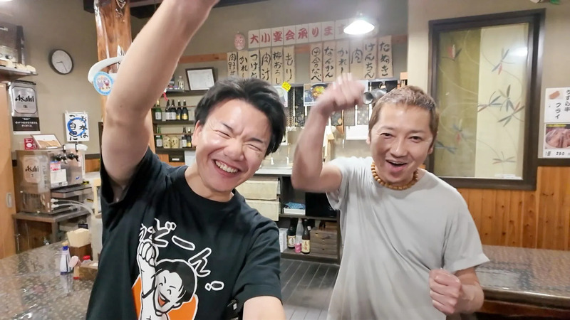 『手打 ここらの田舎うどん なんかん』店主の新井成利さんと、「うっどーん！」記念の一枚