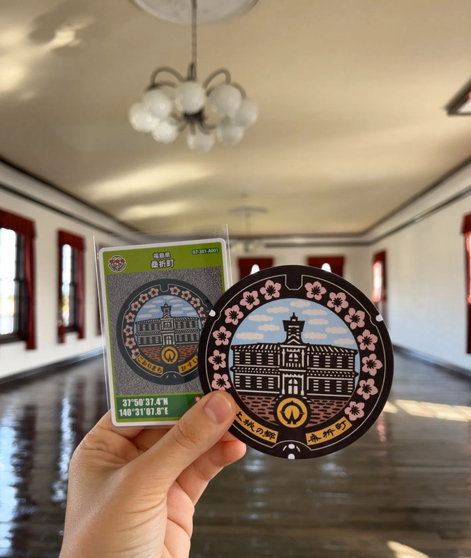 ピカピカに磨き上げられたレンガ式風の床をバックにマンホールカードを撮影