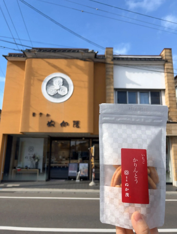 お店の入り口をバックに、「ぬか茂のかりんとう」を撮影