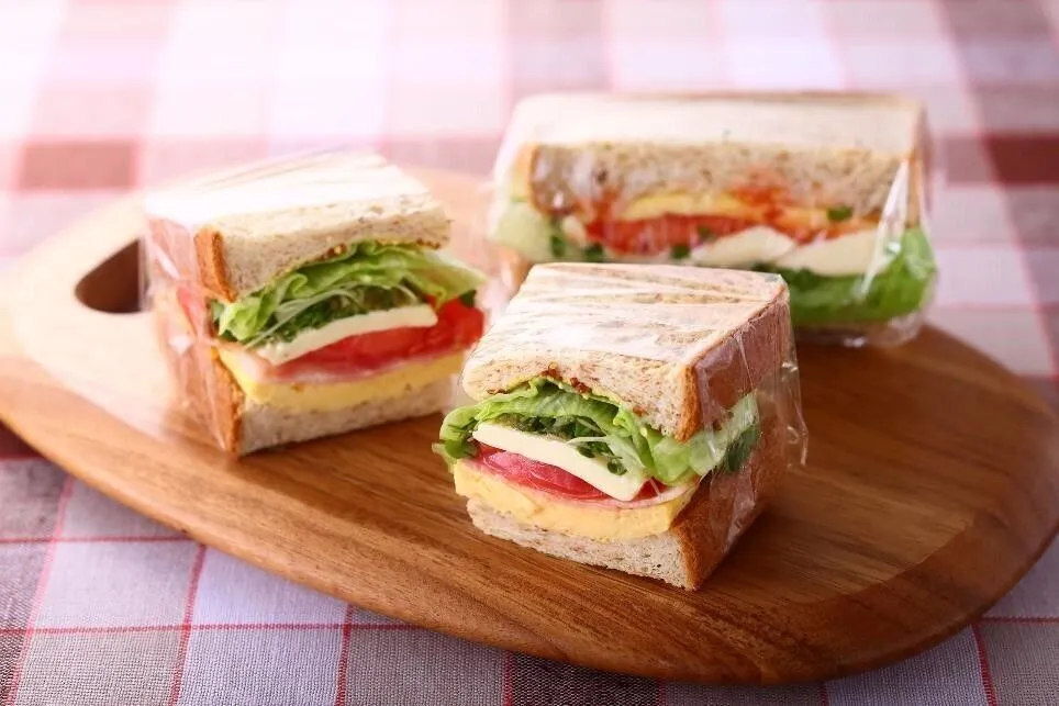 ラップを広げて③をのせ、①、②、スプラウト、パンの大きさに丸めたレタスをのせ、③でサンドし、ラップで包む。同様にして計2個作り、半分に切る。