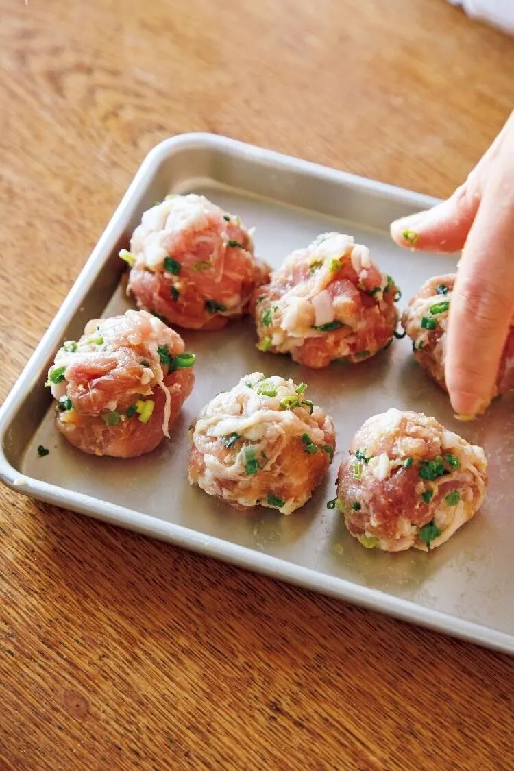 万能ねぎは小口切りにする。ボールに豚こまを入れ、Aの下味の材料を加えて全体に混ぜる。万能ねぎを加え、さっと混ぜる。小麦粉をふりかけてさっと混ぜ、10等分して丸める。片栗粉を薄くまぶし、そのまま5分おく。

（画像：10等分して丸める）