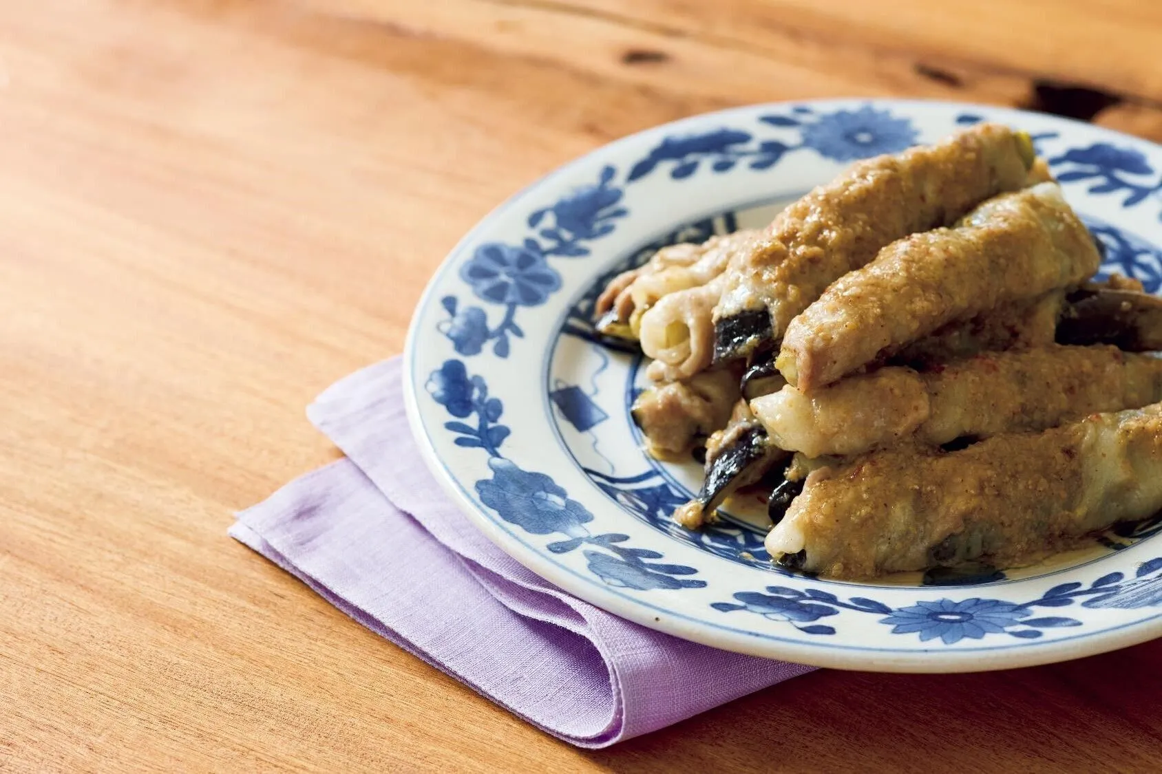 なす1切れに豚肉を1枚ずつらせん状に巻く。直径約24cmの耐熱皿に並べ入れ、Aをまんべんなくかける。ふんわりとラップをかけて電子レンジ（600W）で8分ほど加熱し、そのまま2分ほど蒸らす。ラップをはずし、肉巻きを1本ずつころがして蒸し汁をからめる。