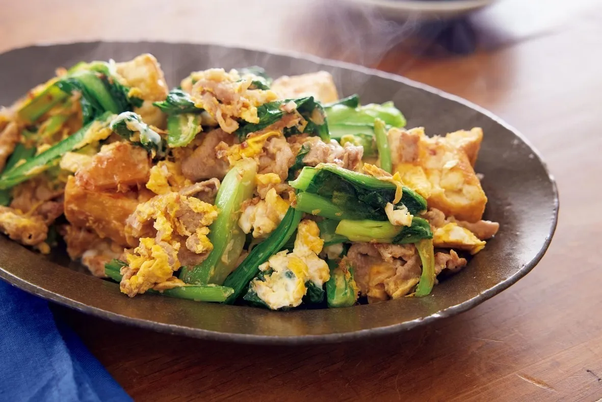 フライパンにごま油を中火で熱し、豚肉を入れて塩、こしょうをふり、1分ほど炒める。小松菜、しょうがを加えてさっと炒め、フライパンの端に寄せる。厚揚げを加え、両面を1分ずつ焼き、酒をふる。削り節、しょうゆを加えて混ぜ、溶き卵を回し入れて、卵が固まるまで全体を炒め合わせる。