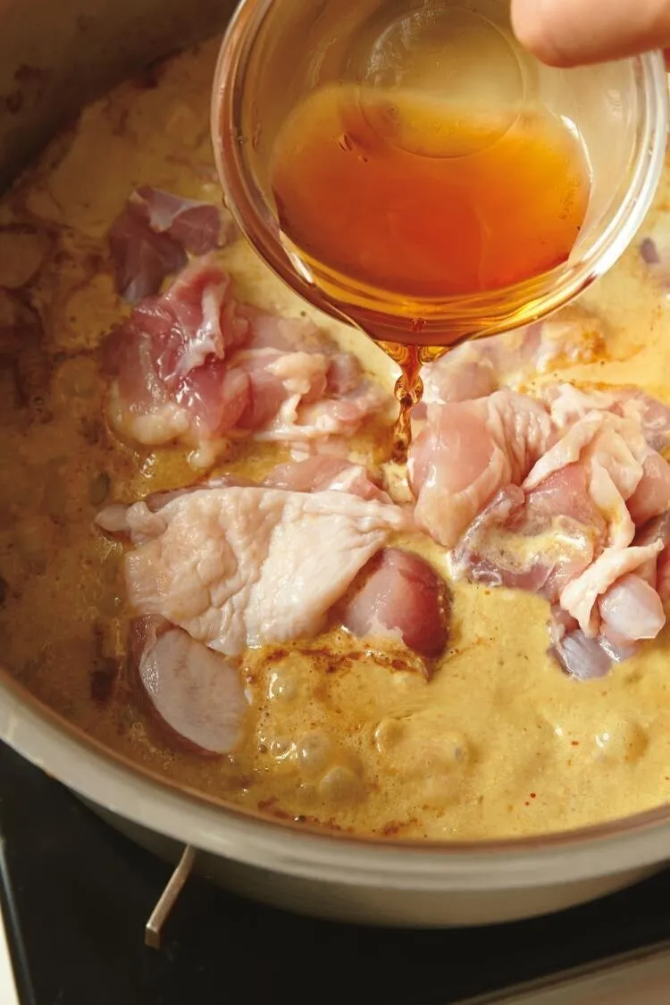 水1カップと、ココナッツミルク、残りのピーナッツを加え、煮立ったら鶏肉、ナンプラーと、砂糖を加える。

（画像：ナンプラーを加える。）