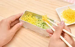 酢飯を半量つめ、細切りにしたキュウリと、薄焼きたまごをのせる。