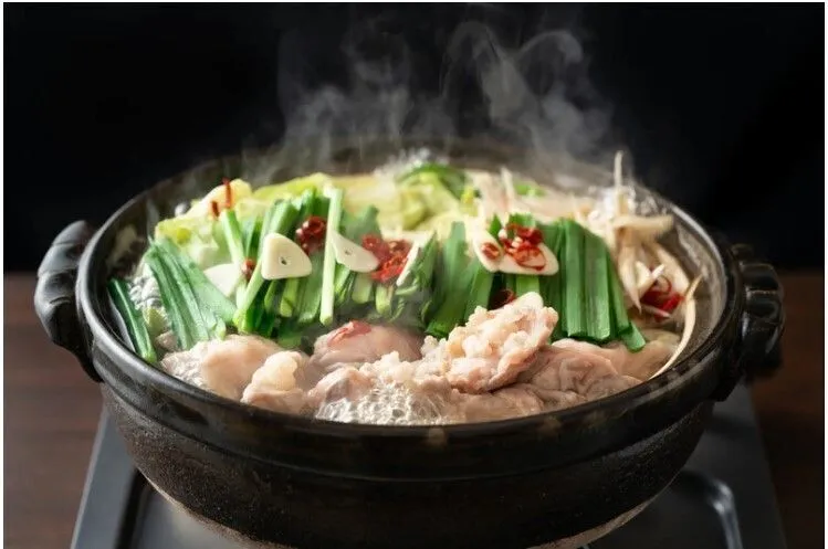 鍋にごぼうとキャベツを入れて加熱する。再び煮立ったら、下処理した牛もつ、にんにく、豆腐を加え、輪切り唐辛子とすりごまを振り入れる。最後ににらを加えて、煮えたら「もつ鍋」の完成。