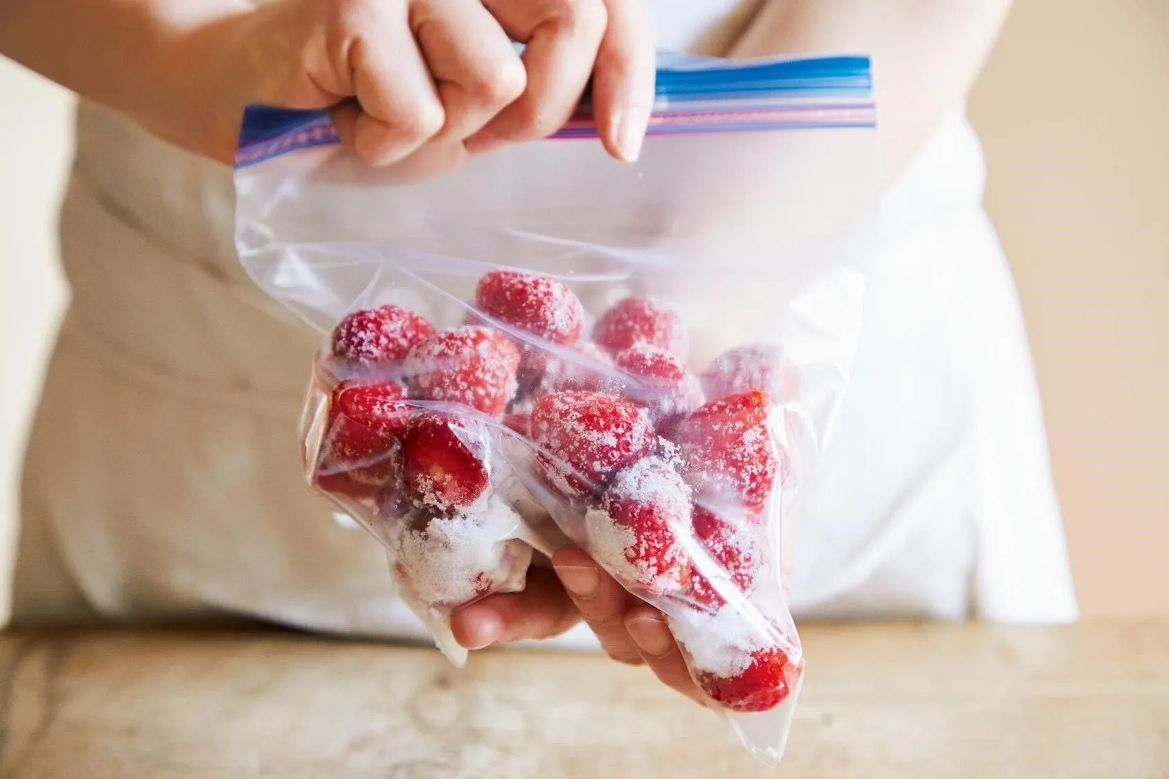 冷凍用保存袋にいちご、砂糖を加える。口をかるく閉じて振り、いちごに砂糖をまぶす。

（画像：いちごに砂糖をまぶす。）