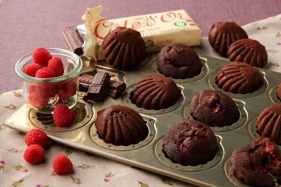 ③の半量を型に等分に絞り入れ、ラズベリーを等分にのせる。残りの③をラズベリーにかぶせるように等分に入れ、オーブンで10～12分焼く。